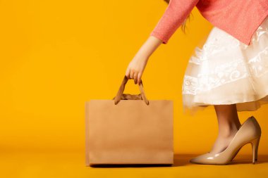 sarı arka plan üzerinde alışveriş çantası ile genç kadın