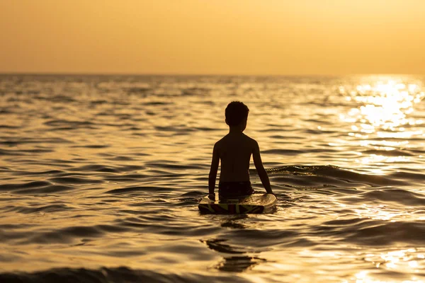 Silhuett av ett barn på en solnedgång bakgrund i havet eller havet på en strand på sommaren — Stockfoto