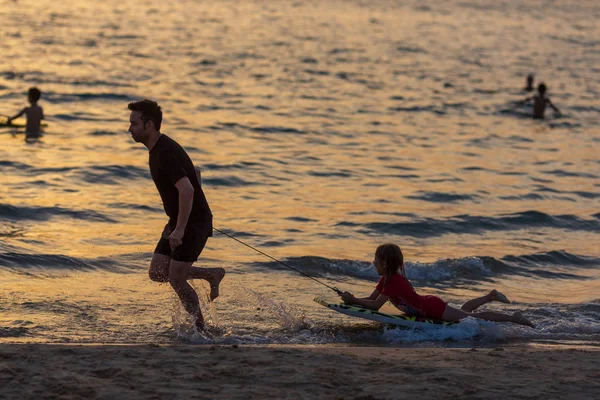 Silhuett av en lycklig far och hans dotter på stranden vid solnedgången tid — Stockfoto