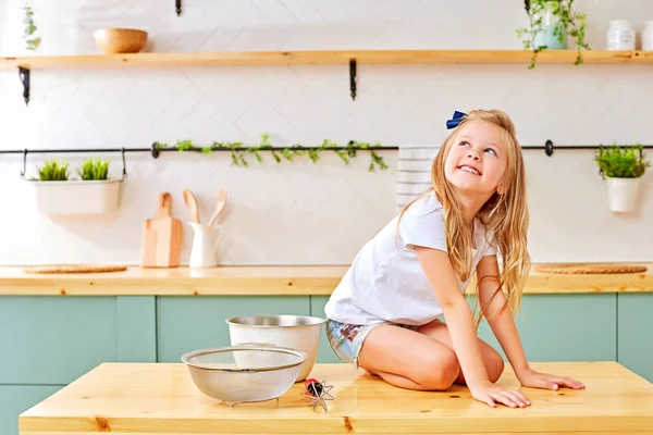 Niña sentada en la mesa de madera de la cocina — Foto de Stock