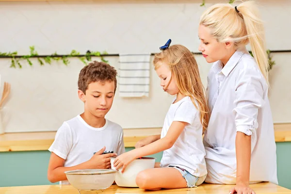 Mamá está horneando galletas con sus hijos en la cocina casera — Foto de Stock