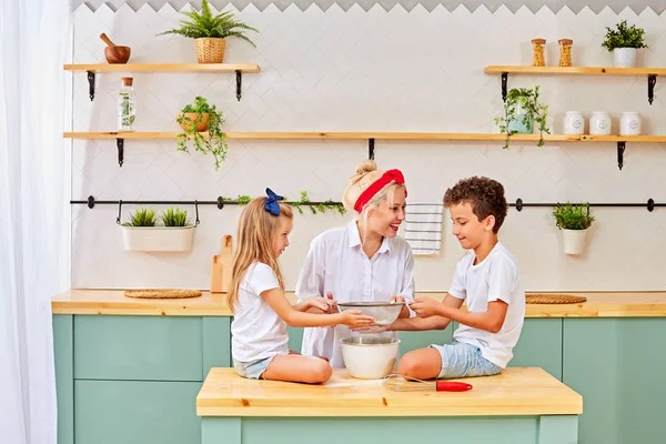 Mamá y sus encantadores hijos hacen albóndigas, pasteles, galletas, pizza, pasteles — Foto de Stock