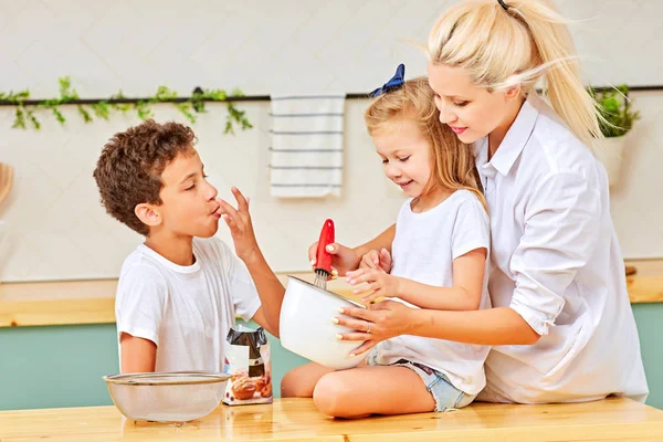 Familia feliz niños divertidos y mamá están preparando la masa, hornear galletas en la cocina — Foto de Stock