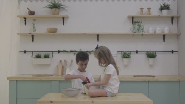 As crianças são cozinhadas e jogadas com farinha e massa na cozinha. cor neutra — Vídeo de Stock