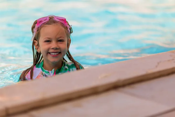 Bébé fille souriante portant des lunettes de bain dans la piscine — Photo