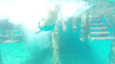 Sportif atlama oğlan yapar iskele çevirir içinde turkuaz mavi deniz, yavaş hareket