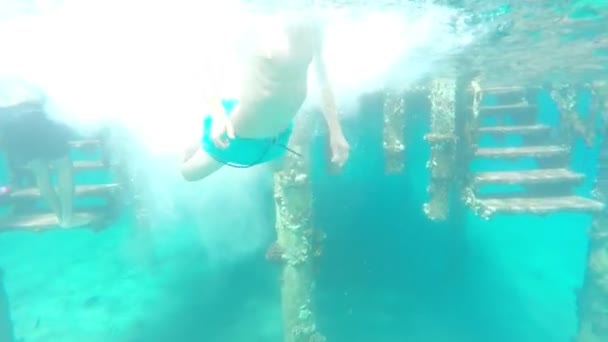 Sportovně skákací kluk dělá molo v tyrkysově modrém moři, pomalý pohyb — Stock video