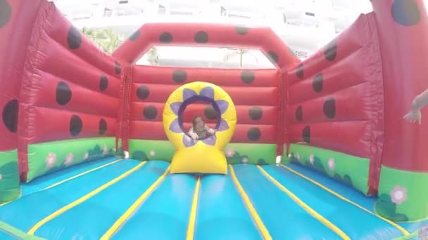 Mała piękna dziewczyna skoki na nadmuchiwane trampoliny — Wideo stockowe