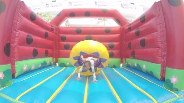 Slow Motion: Little beautiful girl jumping on an inflatable trampoline — Stock Video