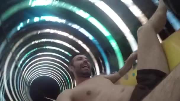 Ein junger Mann rutscht an der Wasserrutsche im Aquapark ab. fällt mit vielen Spritzern ins Wasser — Stockvideo