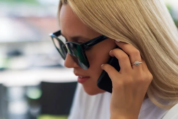 Nahaufnahme Mädchen mit Sonnenbrille telefoniert, während sie in einem Café sitzt — Stockfoto