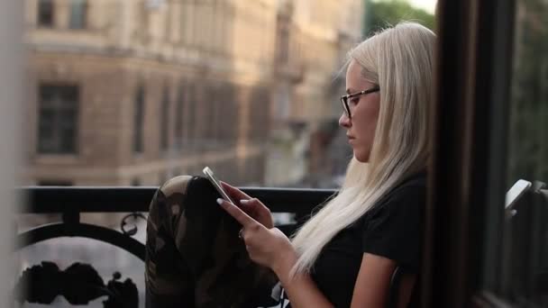 Frau im Urlaub sitzt mit Smartphone auf Balkon — Stockvideo