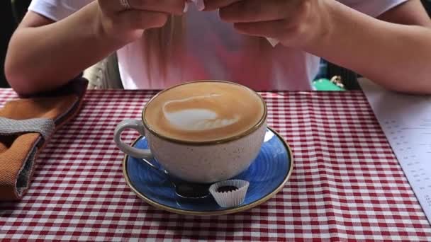 Close-up van de vrouw handen zetten suiker op een kopje koffie en string, in een café — Stockvideo