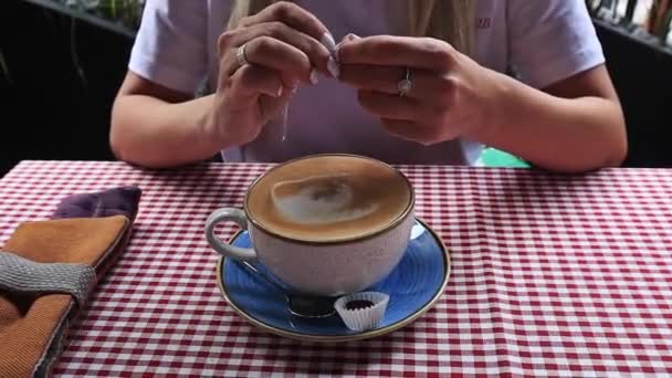 Kvinnor hand hälla socker i kopp med cappuccino — Stockvideo