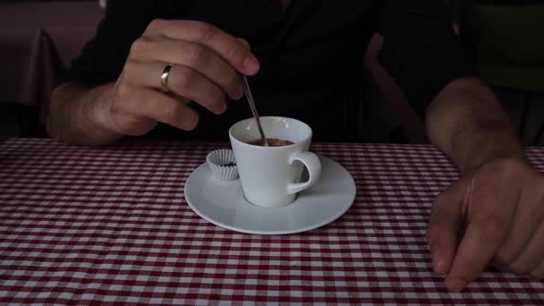 Pria ini menggunakan sendok untuk mengaduk kopi dalam cangkir putih gerakan lambat — Stok Video