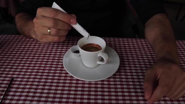 Κοντινό κομμάτι ενός Man χέρι ξεσηκώνει τον καφέ σε ένα φλιτζάνι με ένα μικρό κουτάλι αργή κίνηση — Αρχείο Βίντεο