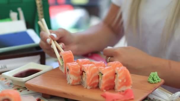 Mujer joven en la cafetería comiendo sushi con palillos. primer plano — Vídeo de stock