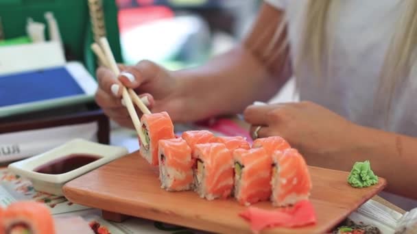 Närbild skott av kvinnlig hand med ätpinnar Dunks stilfullt som sushi in i sojasås — Stockvideo
