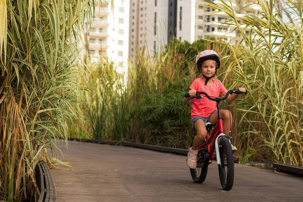 Niño feliz monta una bicicleta en carril bici. Ciclista niña disfruta del buen tiempo y el ciclismo — Foto de Stock