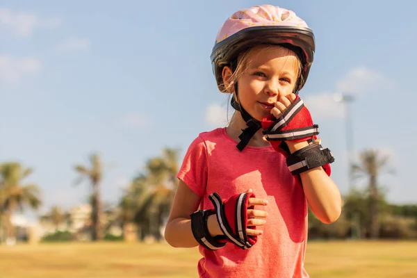 Щаслива маленька дівчинка в шоломі та ручній зброї грає в парку — стокове фото