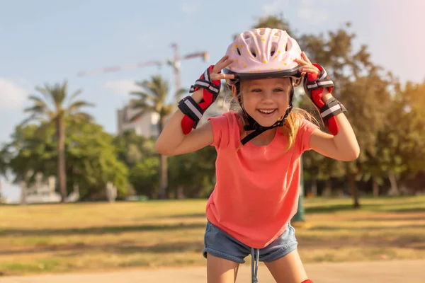 Маленька дівчинка в шоломі і роликових ковзанах в парку. дитина на відкритому повітрі — стокове фото