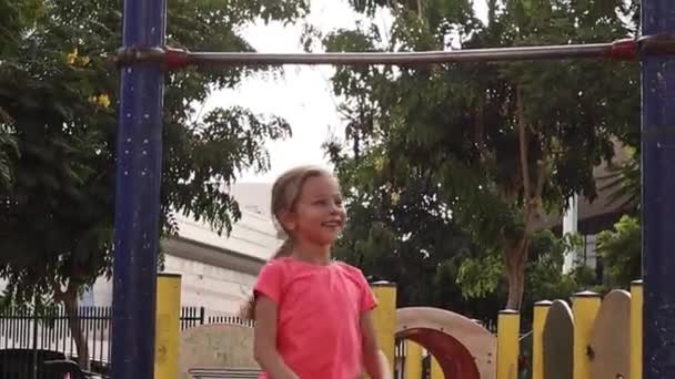 Cute little girl playing on playground and hanging on a horizontal bar — Stock Video