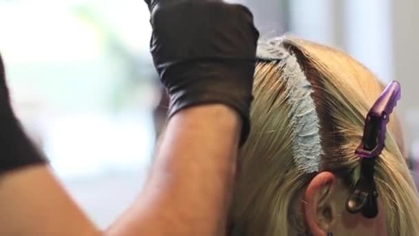 Стилист парикмахер делает волосы окрашивания, блондинки, окрашивания корней волос. Она использует кисть. — стоковое видео