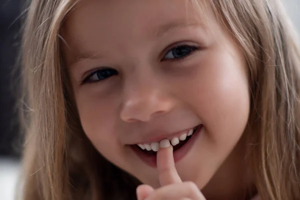 Blue-eyed blond girl laughs and shows the first tooth. childrens teeth, loss