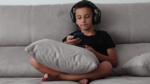 Ragazzo gioca ai videogiochi e parla sullo smartphone, parla felicemente e sorride durante una conversazione . — Video Stock