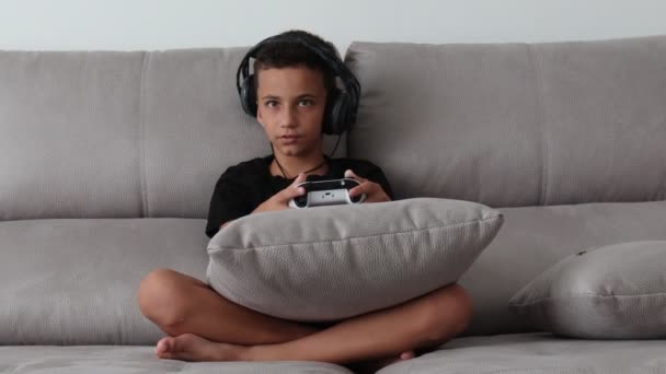 Menino jogando videogames no console o no sofá em casa — Vídeo de Stock