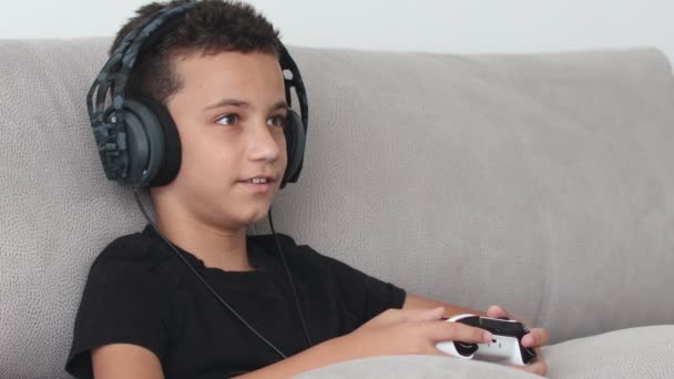 在控制台上玩视频游戏的男孩在家里的沙发上 — 图库视频影像