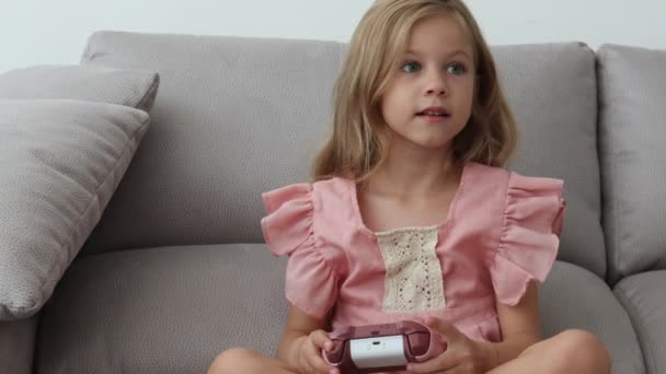 Hemma: söt flicka som leker i video spelkonsol, med joystick controller — Stockvideo