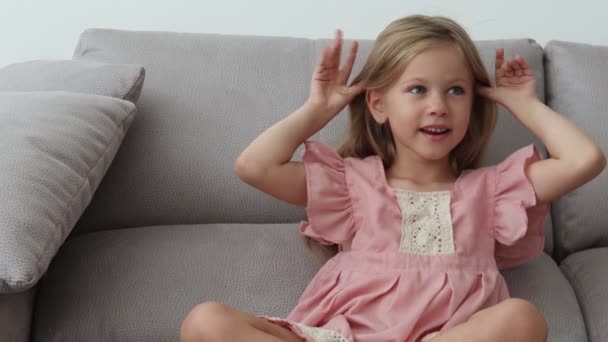 Маленькая девочка смотрит на камеру, улыбается и дурачится — стоковое видео