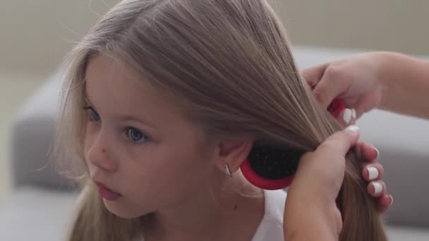 Мама робить своє маленьке волосся дочки, зав'язуючи волосся в хвостик. повільний рух — стокове відео