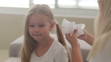 Anne kızlarının saçlarını tarıyor. Elinde saç