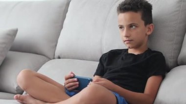 Küçük bebek erkek kanepede genel tasarım cep telefonu ile otururken ellerde gülümseyerek