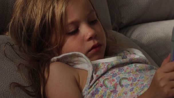 Six years old blonde child in pajamas sleeping lying on the couch, with digital tablet — Stock Video