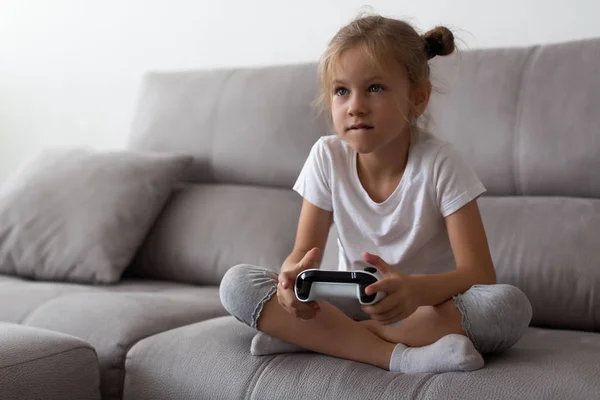 Серьёзная девочка, играющая в видеоигры дома — стоковое фото