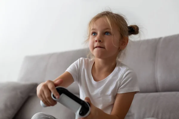 Competitieve meisje spelen met gamepad op de Bank — Stockfoto