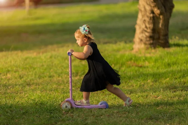 草の上にスクーターに乗って小さな女の子 — ストック写真