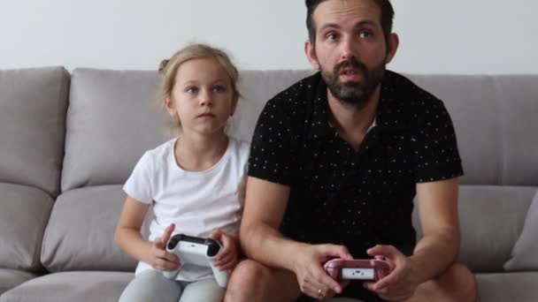 아버지와 어린 아이가 집에서 소파에서 비디오 게임을하고, 조이스틱에 버튼을 누르고. — 비디오