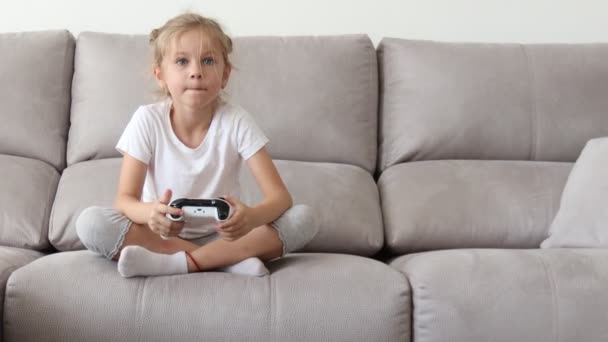 Chica jugando en la consola de videojuegos, usando controlador de joystick. Chica rubia feliz Jugando Video juegos . — Vídeo de stock