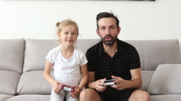 Alegre padre caucásico jugando videojuegos emocionalmente junto con su linda hija ganando — Vídeo de stock