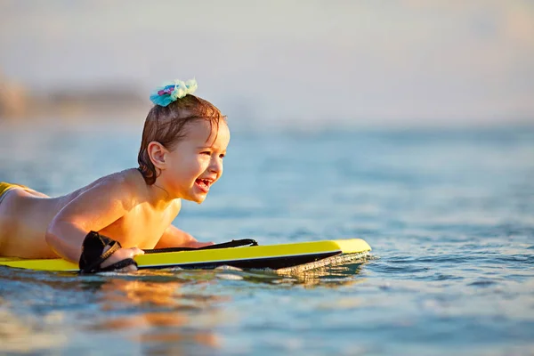 Маленькая девочка побеждает сильные волны во время золотого заката — стоковое фото
