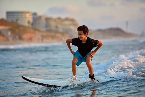 Surfen bei Sonnenuntergang. kleiner Junge beim Wellenreiten bei Sonnenuntergang. Aktiver Lebensstil im Freien — Stockfoto