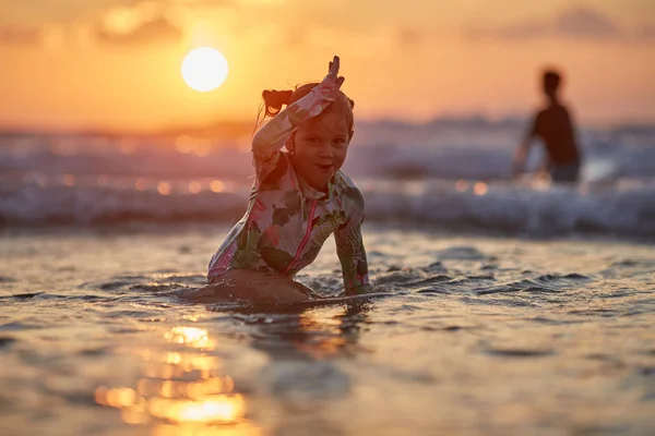 楽しさと海に遊んで幸せな陽気な女の子。夕暮れ時にビーチで遊んでいる女の子 — ストック写真