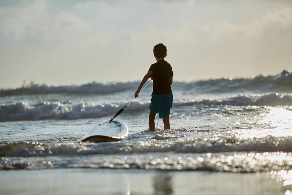 10 éves fiú szörfözik az Israel Beachen Tel-Avivban. A srác meghódítja a hullámokat a szörfdeszkán. — Stock Fotó