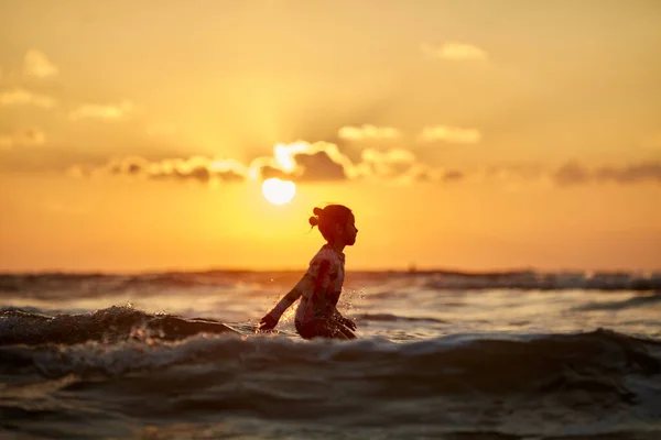 日落时的轮廓，日落时的女孩，轮廓跳跃。 黄昏时在海滩上的生活和活动. — 图库照片