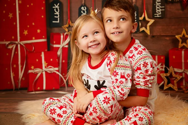 Happy little brother and sister in Christmas pajamas waiting for gifts on Christmas Eve — ストック写真