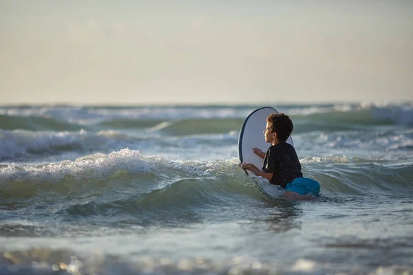 Мальчик разбивает волны на доске для серфинга — стоковое фото